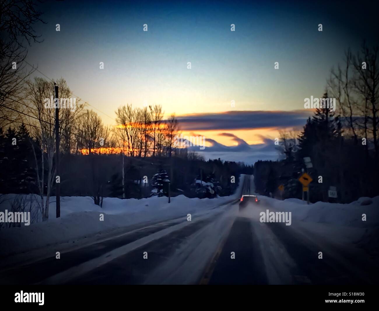 Winter cloud formation over a snowy roadway. Kelvin-Helmholtz Waves in northern Maine. A car passes a Moose Crossing sign in the foreground. - Smartphone Captured Stock Image