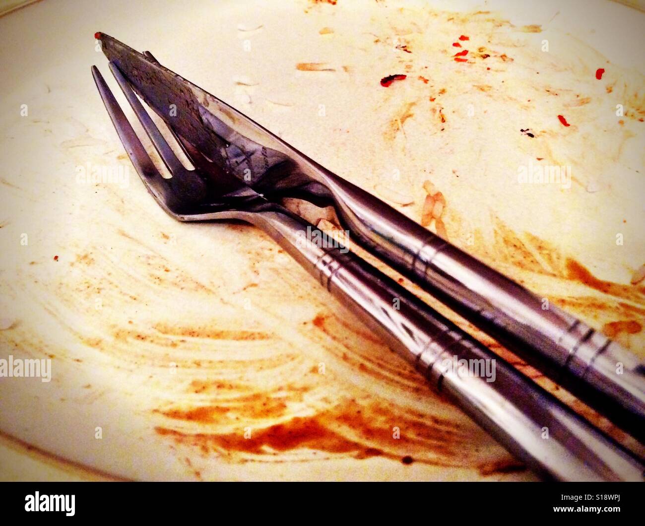 A knife and fork together on an empty but dirty plate Stock Photo Alamy