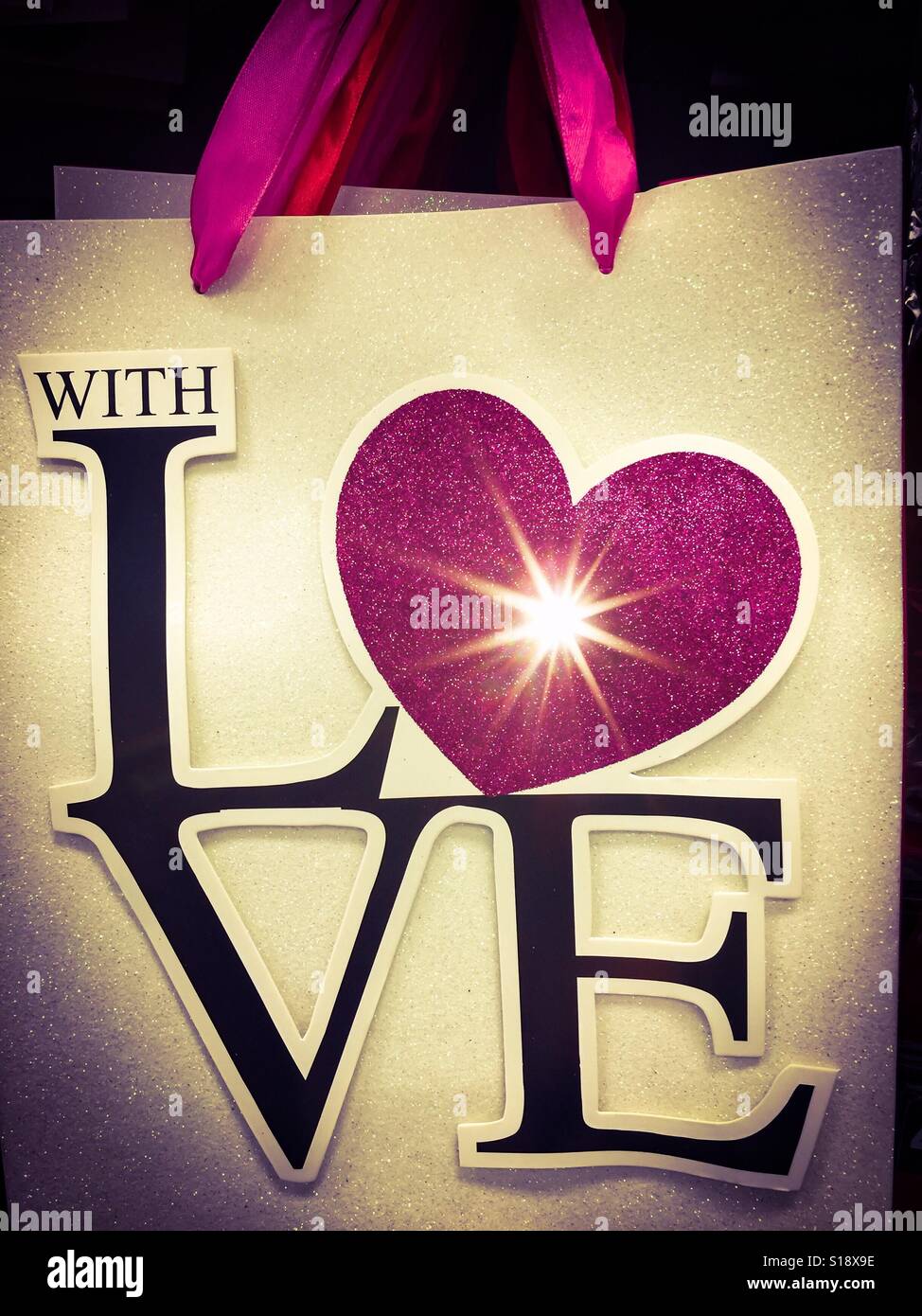 With love theme variation. A heart with a spark replaces the letter O. Bag. Pink handle. A gift bag - Smartphone Captured Stock Image