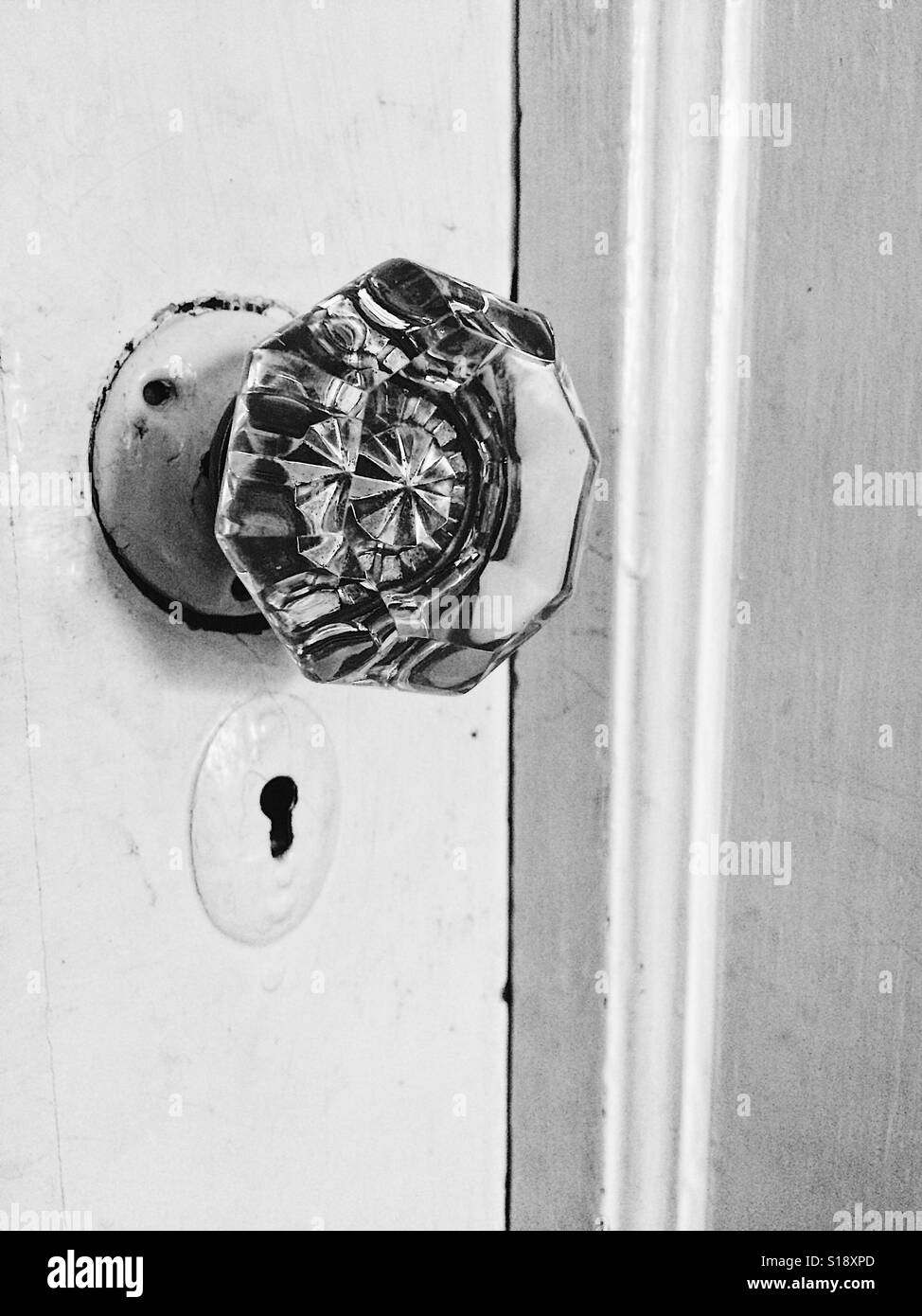 Black and white antique doorknob and keyhole in a white door Stock