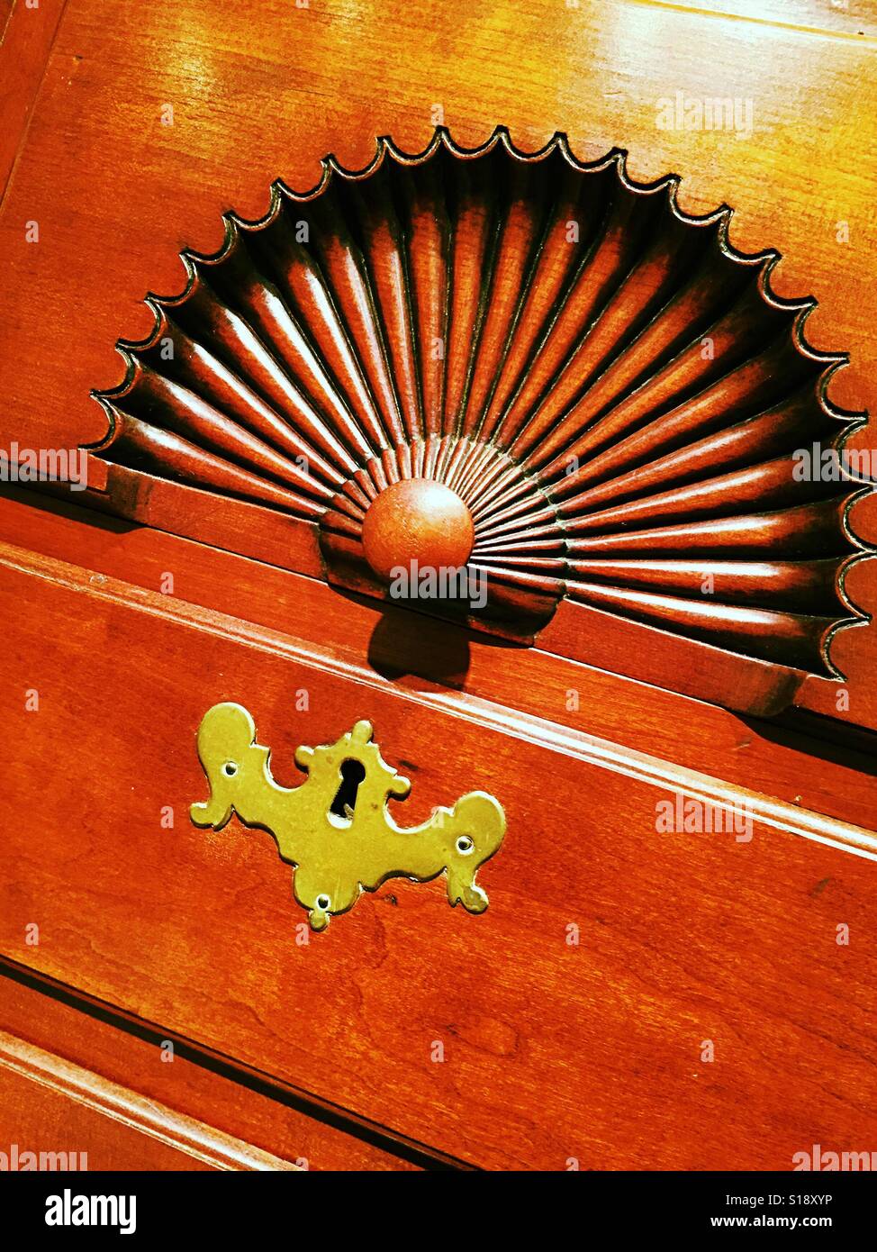 Carved fan and brass  keyhole on antique Chippendale chest USA - Smartphone Captured Stock Image
