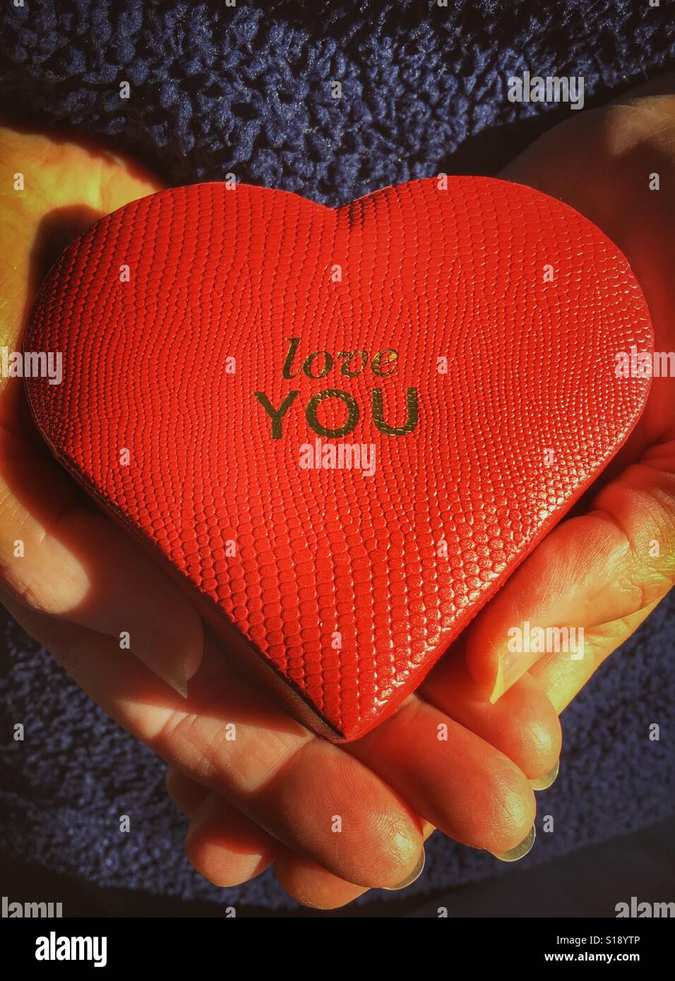 Love you. Red heart shaped box in hands - Smartphone Captured Stock Image