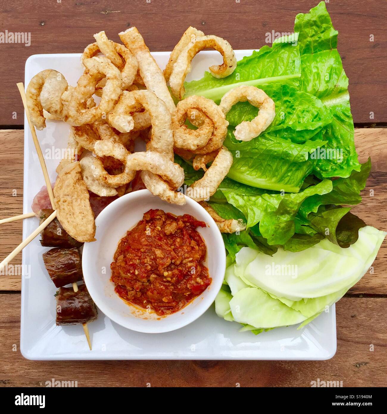 Crispy pork skin, Thai style sour sausages served with nam prik ong and fresh vegetables Stock Photo