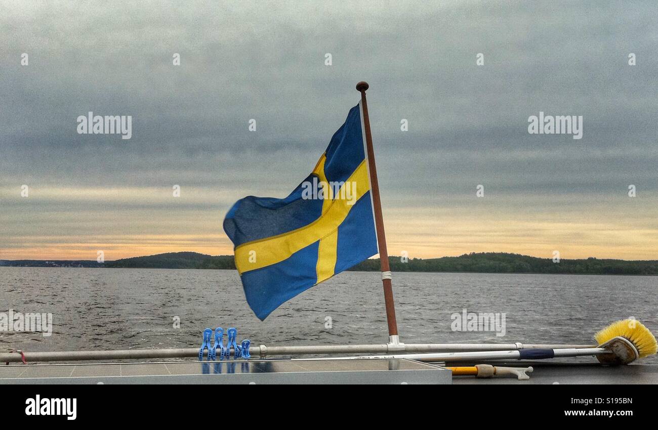 Swedish flag in the aft of a smaller boat on lake Mälaren, outside of Sigtuna in Sweden Stock Photo