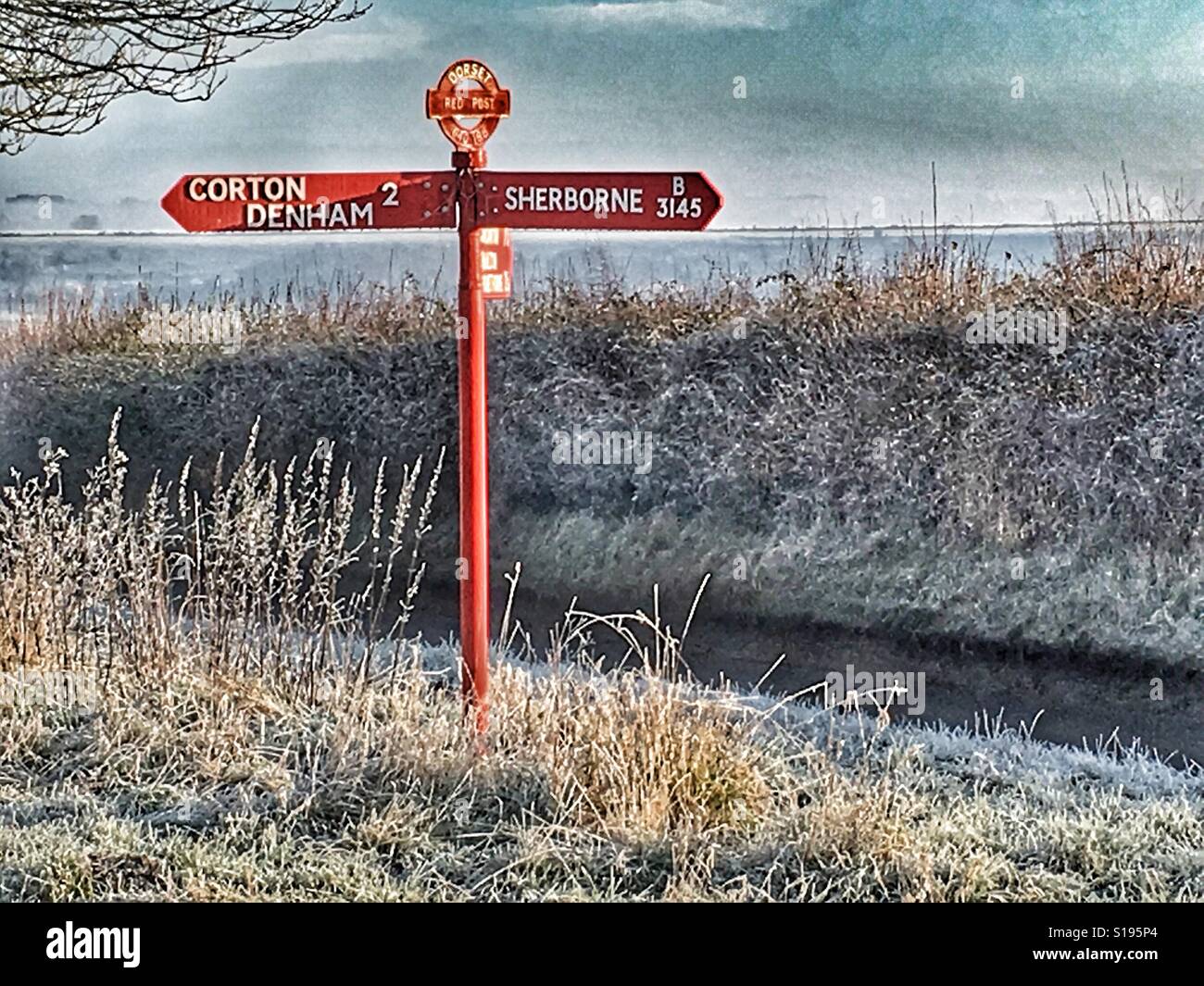 Dorset red signpost, in winter. Directional road sign showing Sherborne and Corton Denham Stock