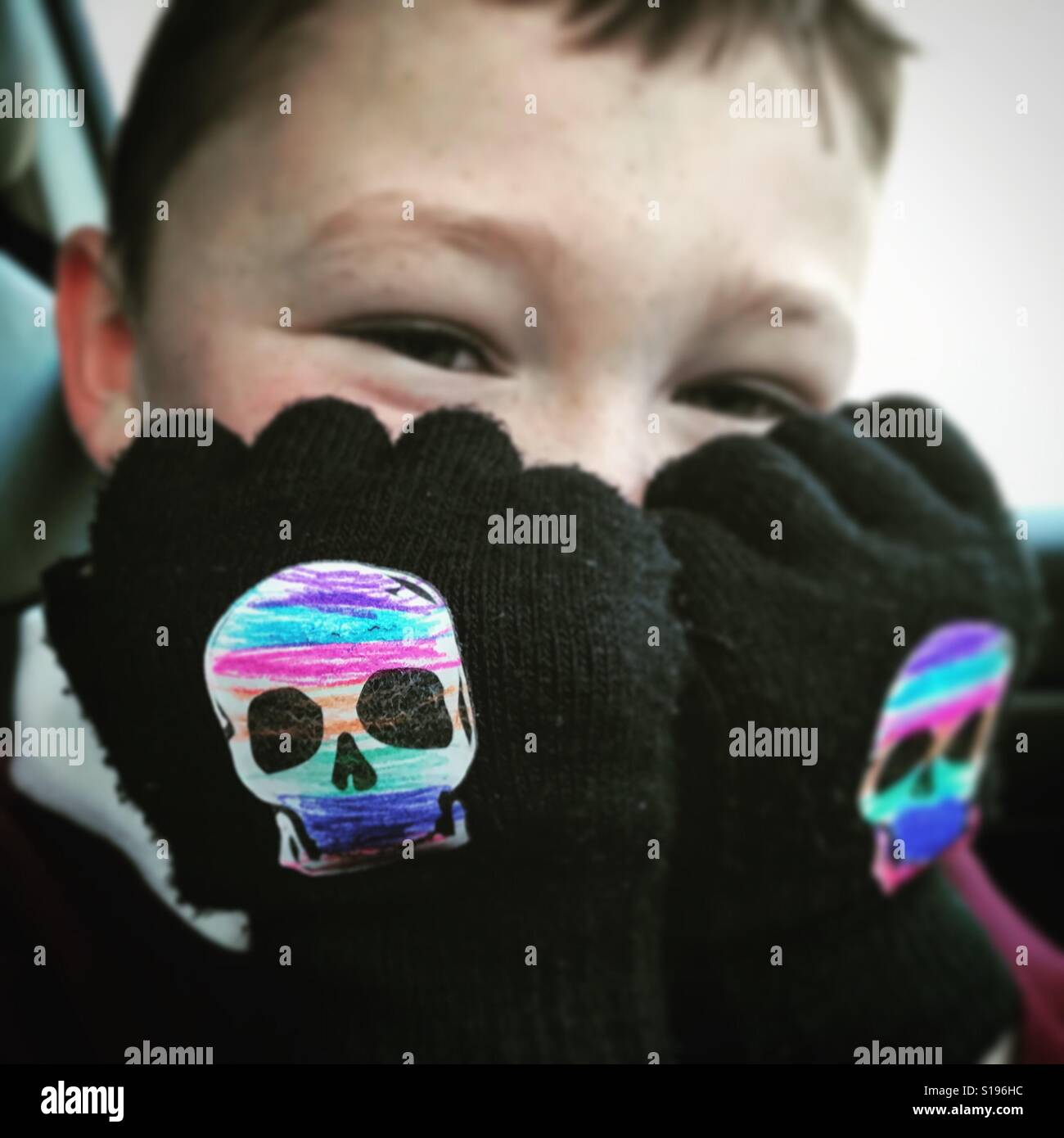 Boy wearing skull gloves that he's coloured in with crayons Stock Photo