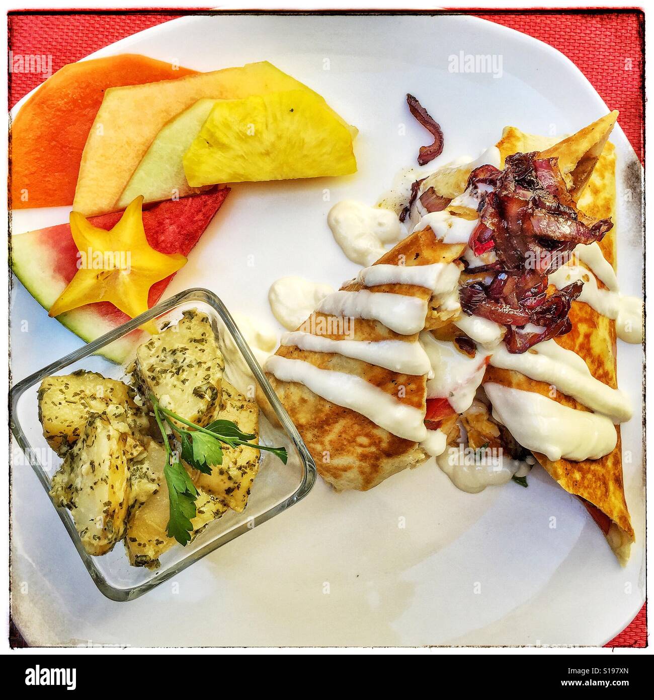 Breakfast burrito, an assortment of fresh fruit, and a dish of potatoes artfully presented at Santana's in Bucerias, Nayarit. Stock Photo