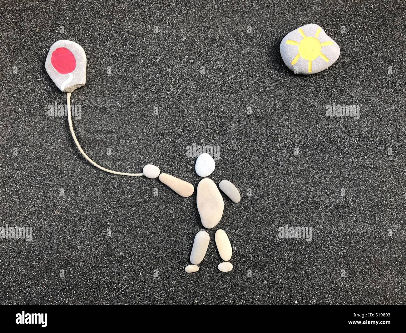 Childhood, conceptual composition with pebbles and stones over black volcanic sand - Smartphone Captured Stock Image