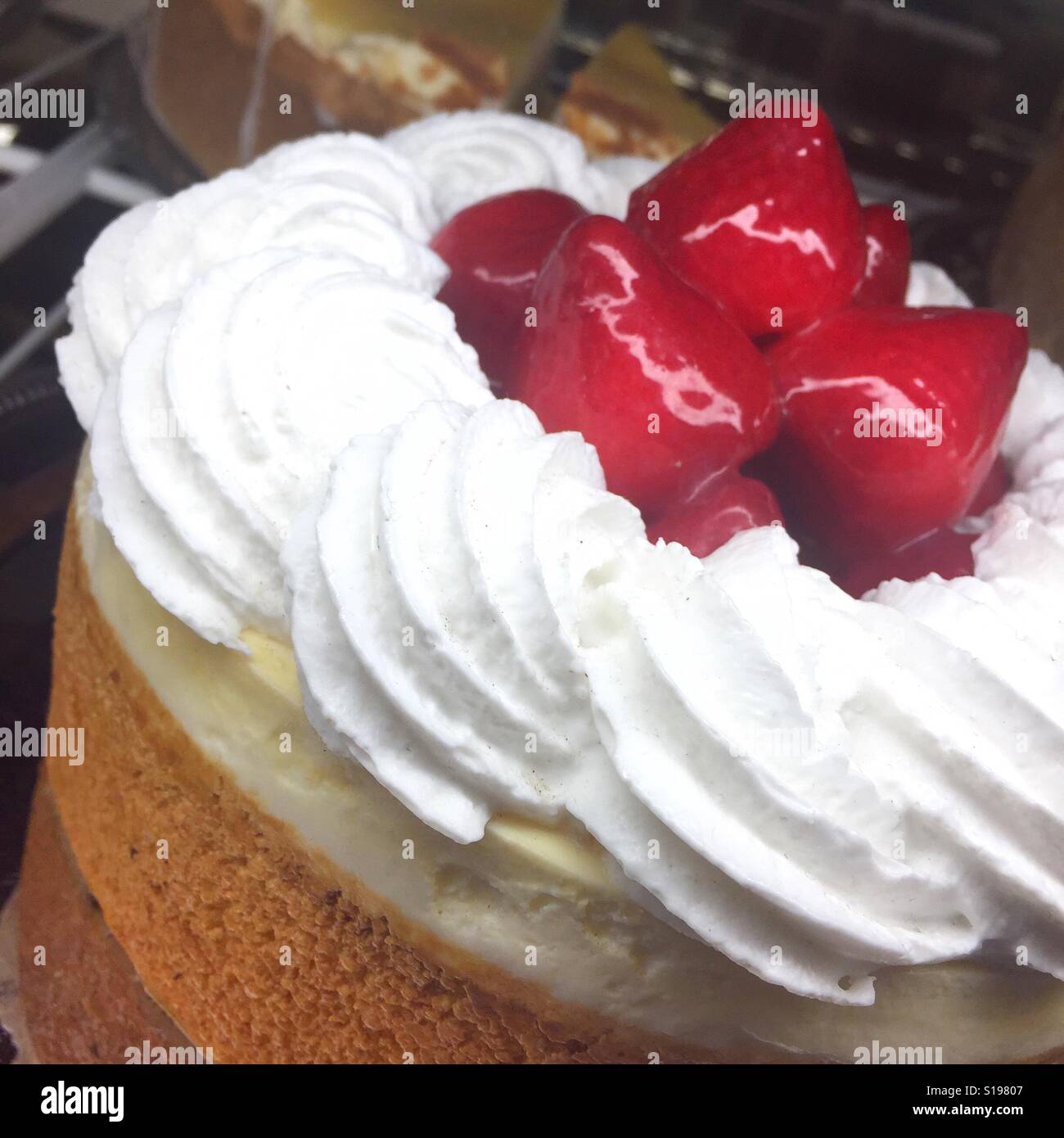 A close up photo of a cheesecake topped with thick white icing and strawberries Stock Photo