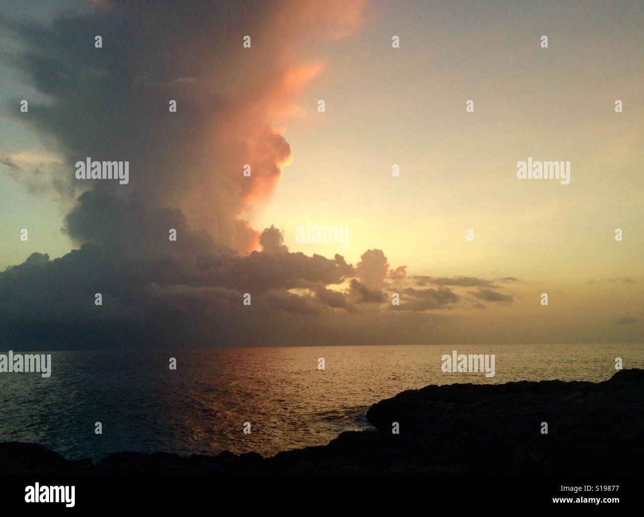 Sunset's last light illuminates a towering thunderstorm over the ocean, West End, Negril, Jamaica - Smartphone Captured Stock Image