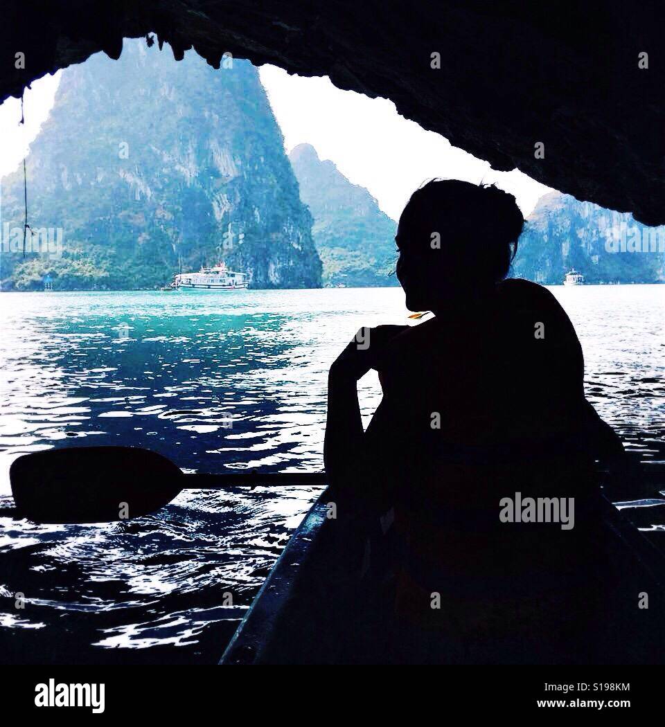 A girl silhouette, kayaking in a cave in HaLong bay, Vietnam Stock Photo