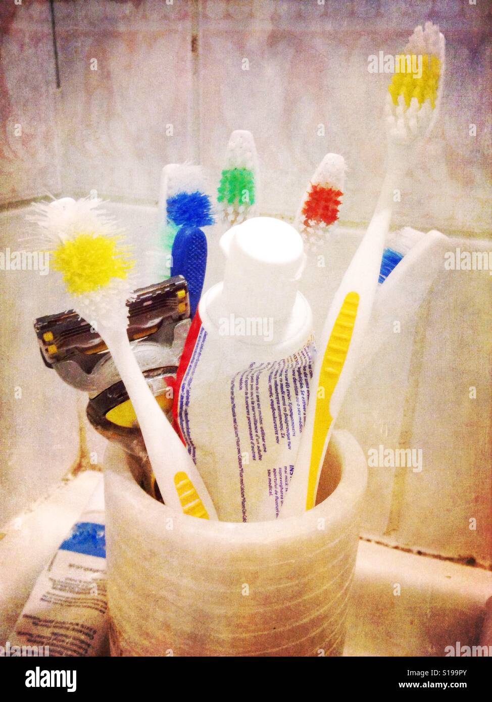 A min in a bathroom containing toothbrushes and toothpaste. - Smartphone Captured Stock Image