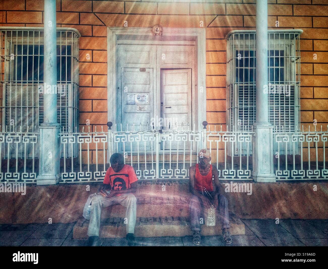 Two Cuban men sitting on the stairs in front of the house Stock Photo