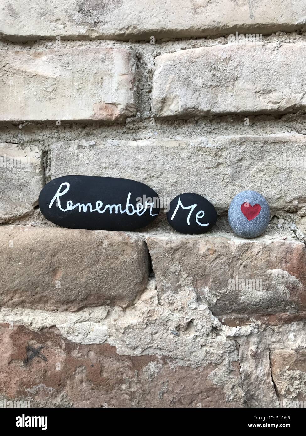 Remember me, conceptual stones composition with carved text over black painted stones and a carved stone heart - Smartphone Captured Stock Image
