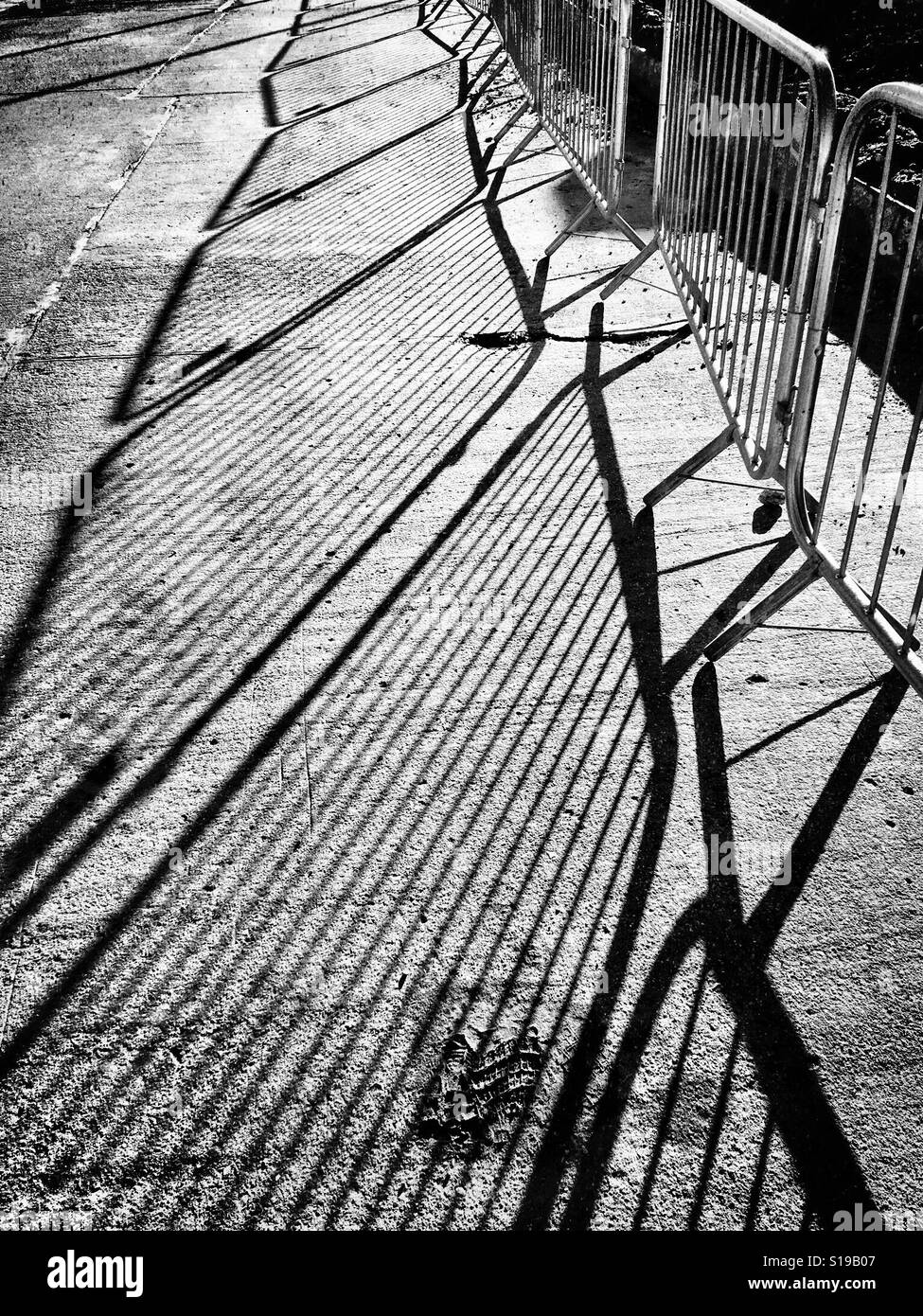 Long, winter shadows of crowd barriers in black and white - Smartphone Captured Stock Image