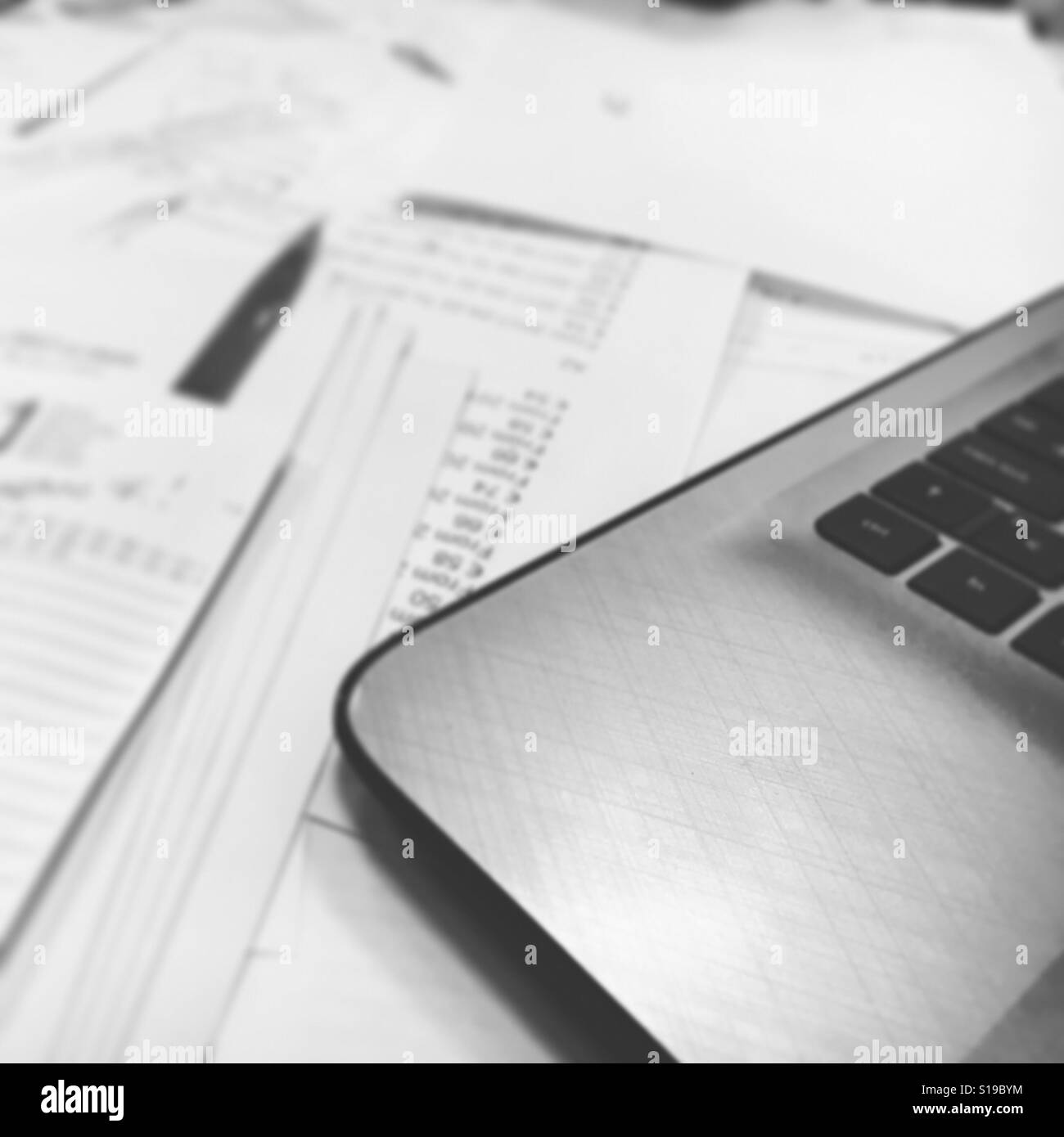 Blurred business table full of papers and laptop in black and white Stock Photo
