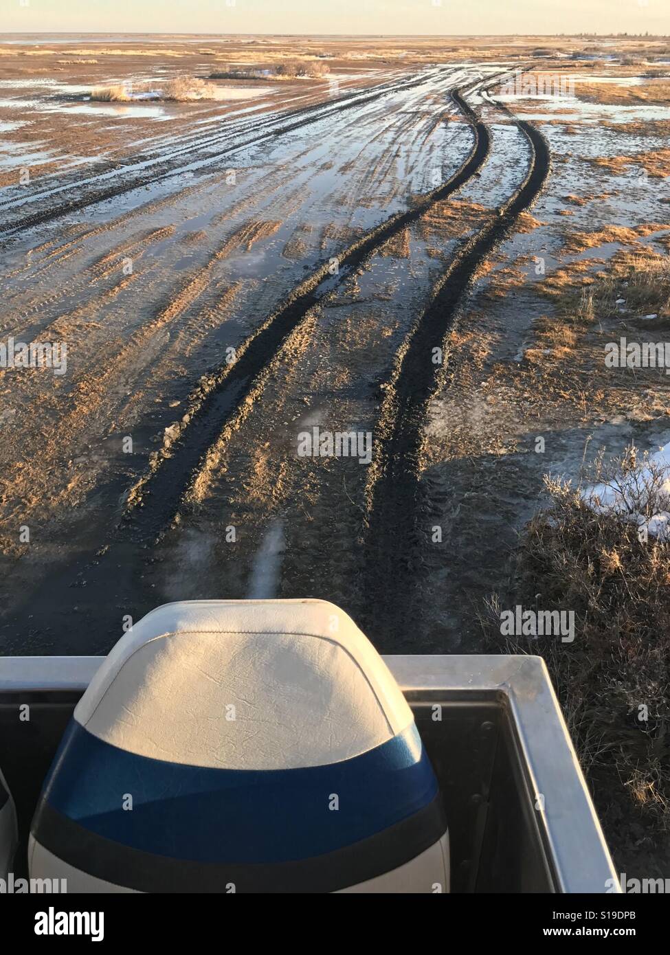 An portion of an overland vehicle in front of the muddy tracks made in the melting taiga. - Smartphone Captured Stock Image