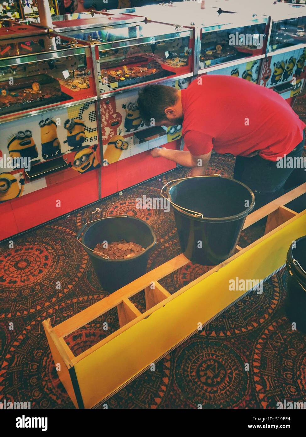 Young man in Games Arcade removing coins from machines Stock Photo