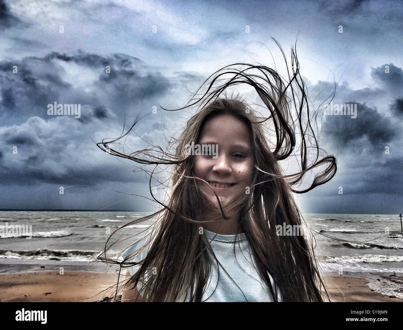 Pre-teen girl at the beach on a windy day. Stock Photo