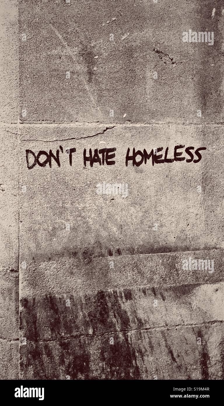 A sepia photograph of graffiti reading "DON'T HATE HOMELESS" on a wall in a town in the UK Stock Photo