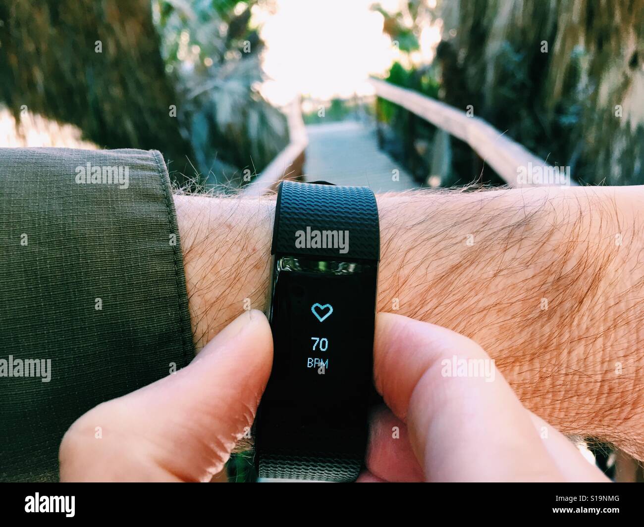 Man checks his heart rate of 70 beats per minute on his FitBit Charge 2 Stock Photo