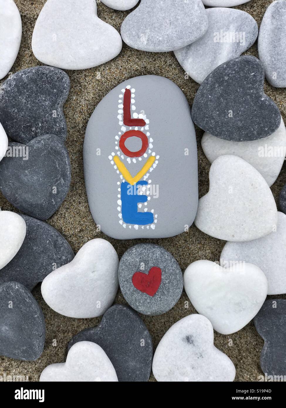 Love stones composed with hand painted and carved stones with heart stones - Smartphone Captured Stock Image