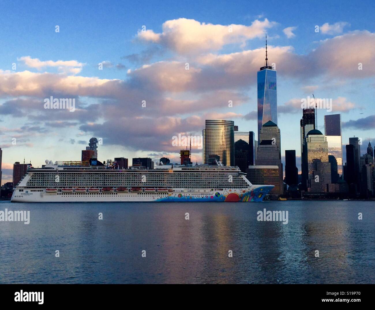 Cruiser sails by Lower Manhattan and Freedom Tower. Stock Photo