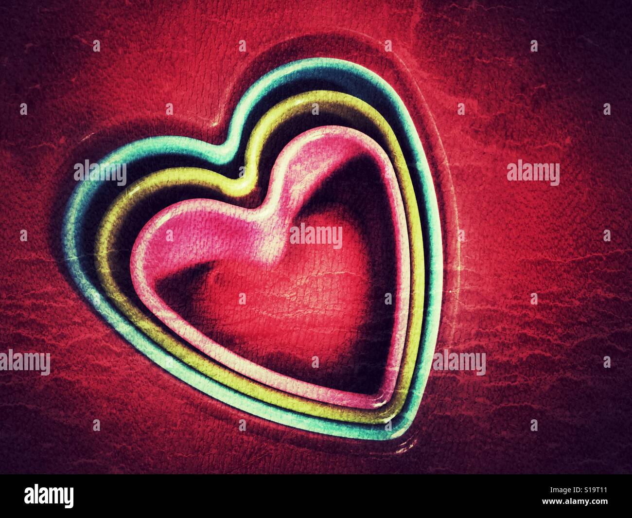 Plastic heart shaped cookie cutters on red - Smartphone Captured Stock Image