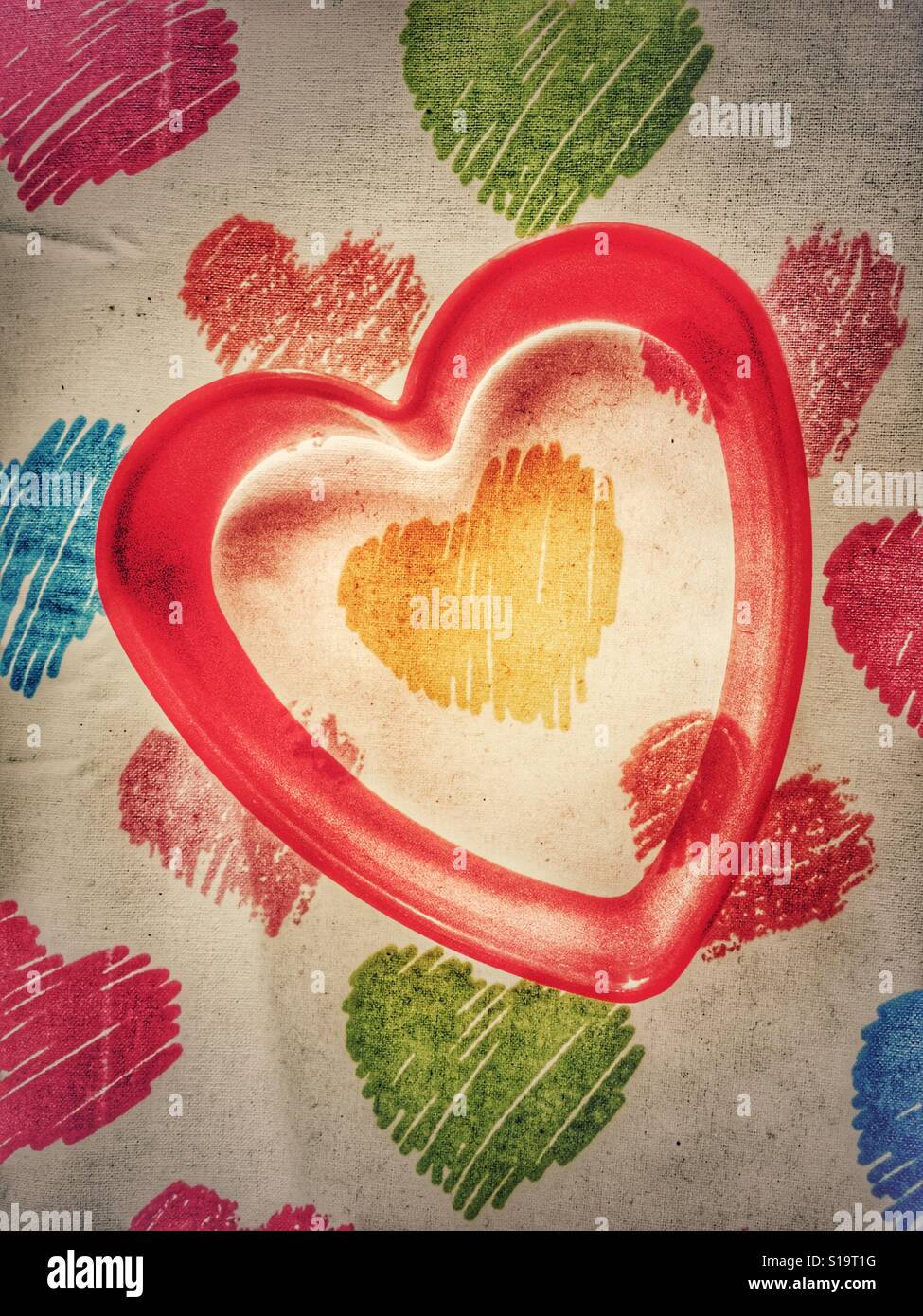 Red plastic heart shaped cookie cutter on heart background - Smartphone Captured Stock Image
