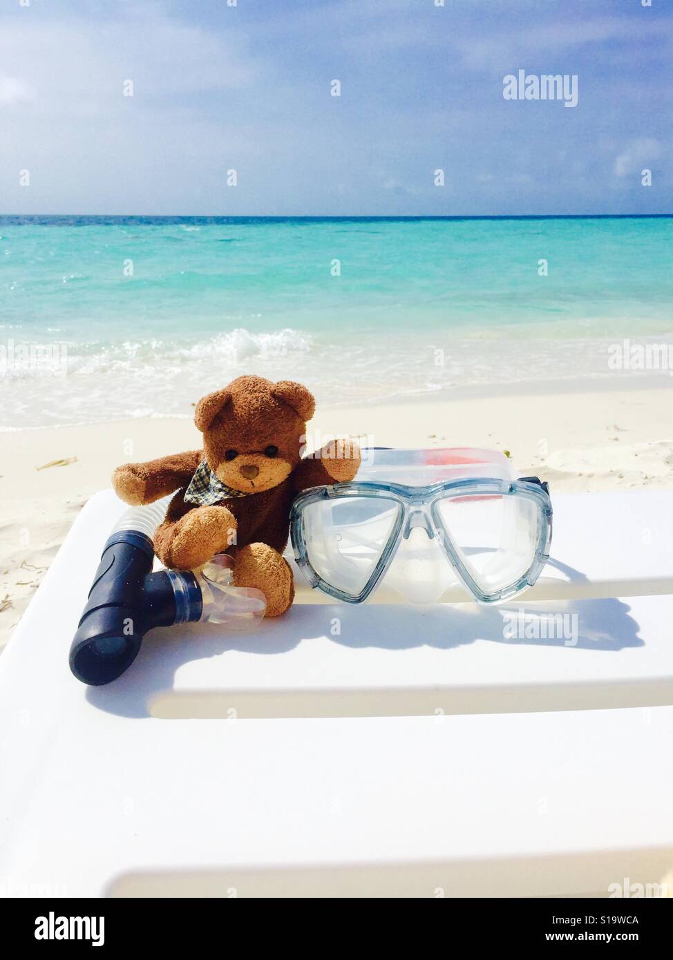 Teddy bear sitting on the beach chair with snorkeling equipment, Maldives Stock Photo