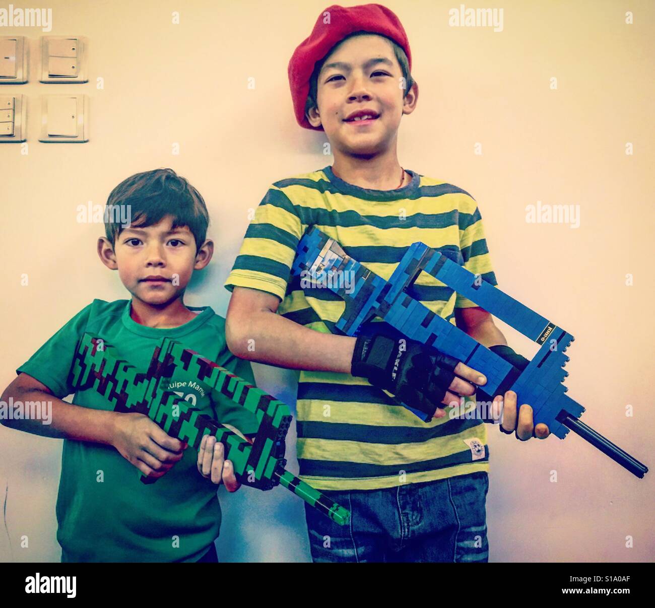Boys playing soldier with plastic machine gun toy Stock Photo