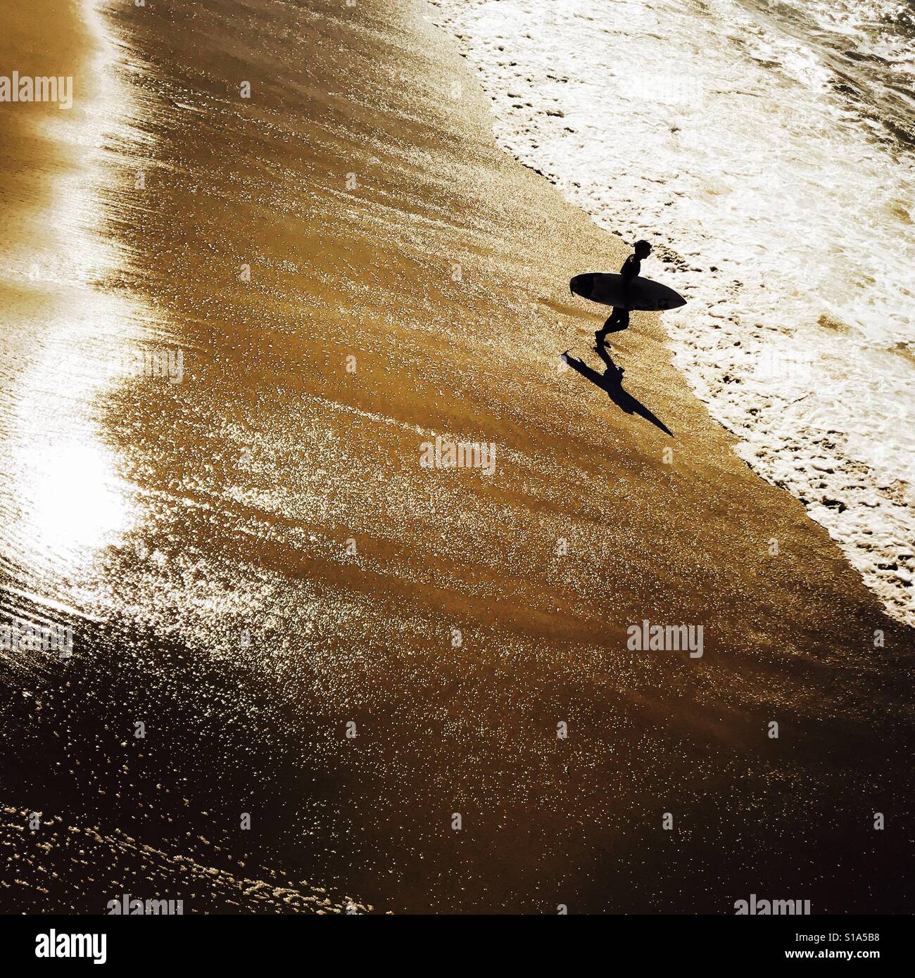 Surfer walking into the surf. Manhattan Beach, California USA. Stock Photo