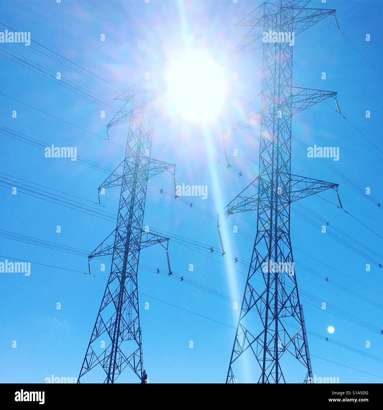 Sun between two electric pylons by K.R. Stock Photo