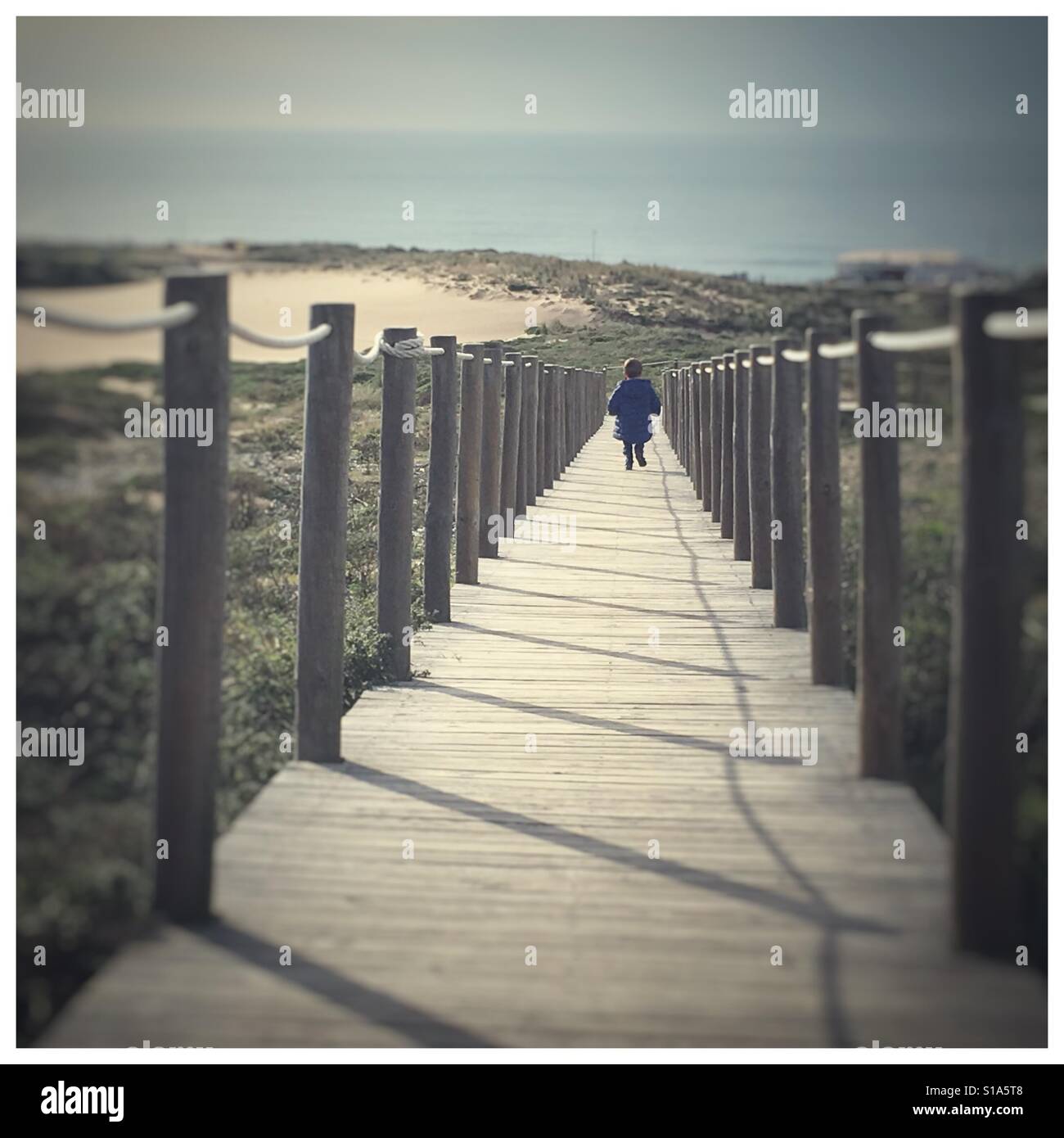 Little boy runs to the sea on a pathway, Duna da Cresmina, Guincho, Portugal. Stock Photo
