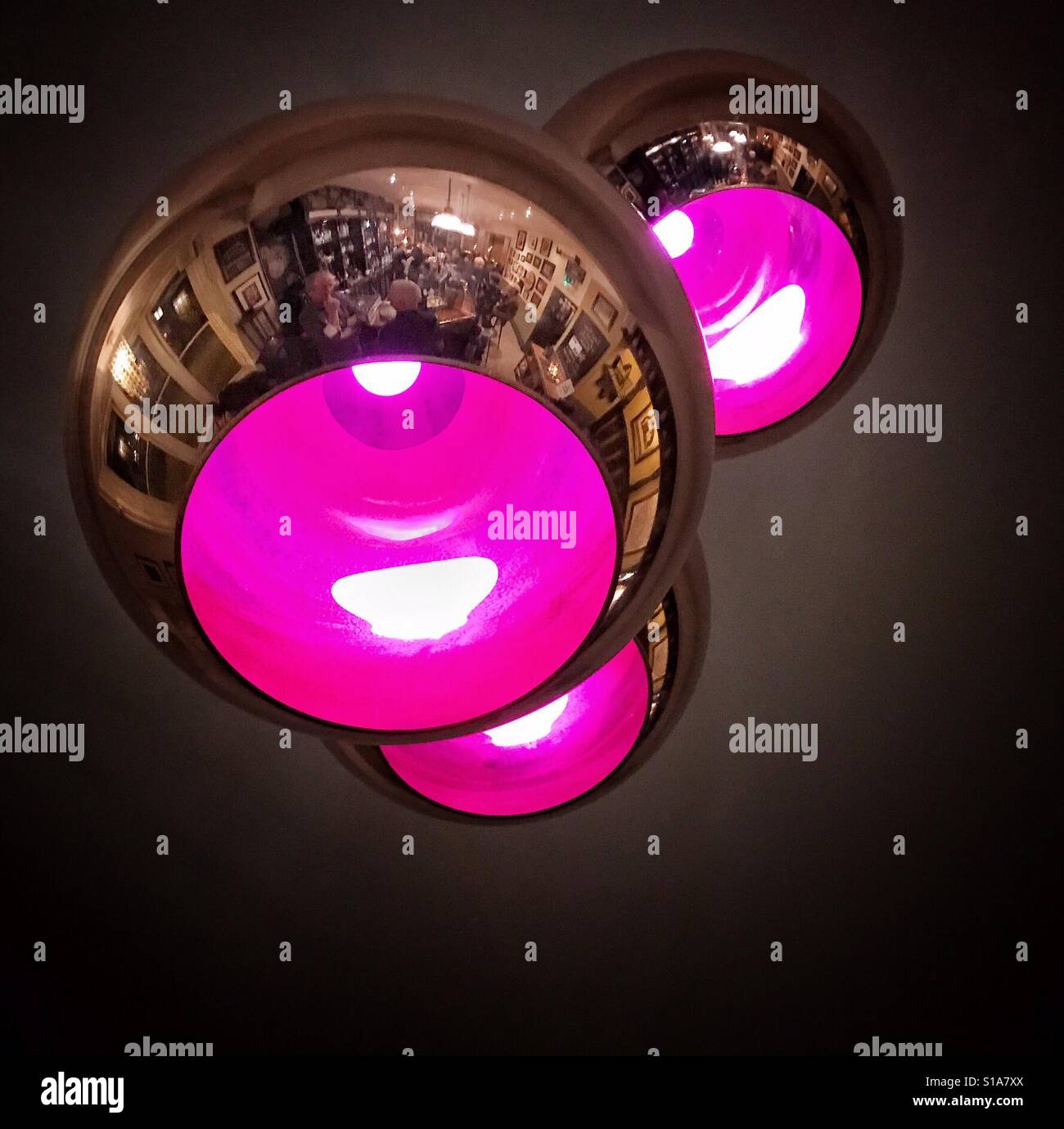 Reflections of the interior of The Sun Pub, Carshalton, London on the polished exterior of ceiling lamps - Smartphone Captured Stock Image