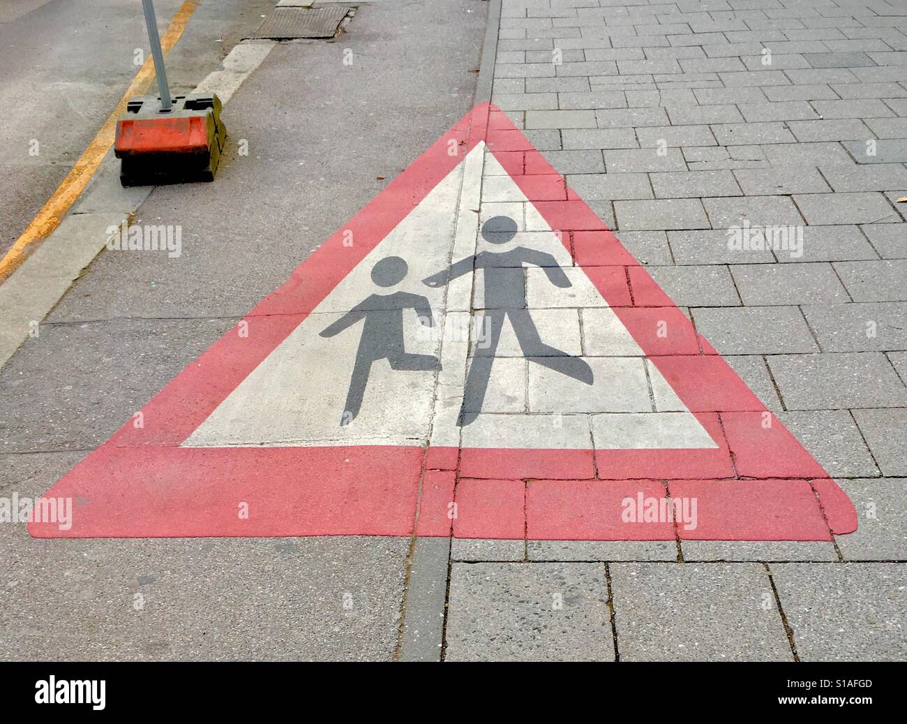 Children Crossing Large Road Sign Painted On The Path. Munich, Germany - Smartphone Captured Stock Image