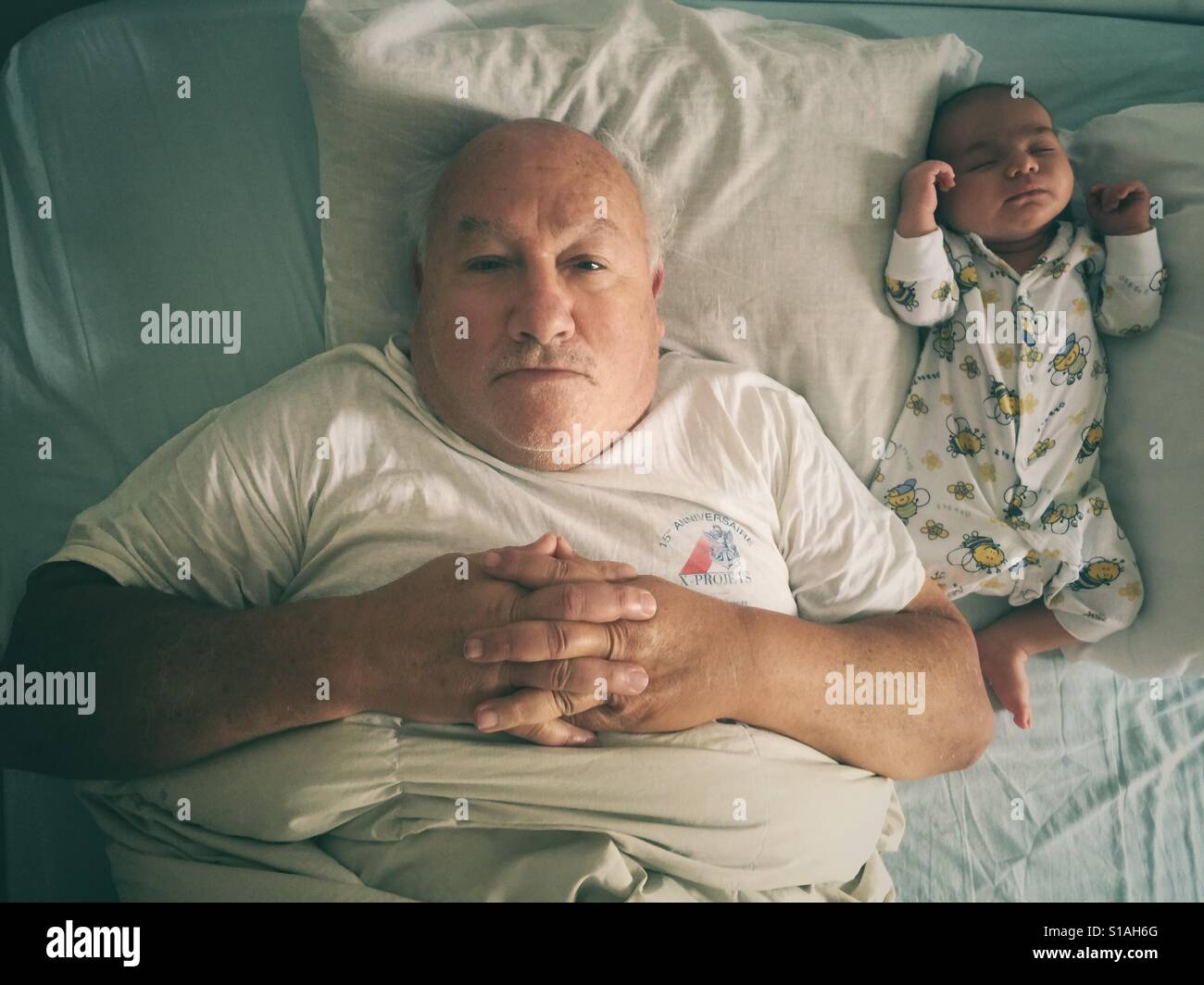 Grand father and newborn baby lying on the bed Stock Photo