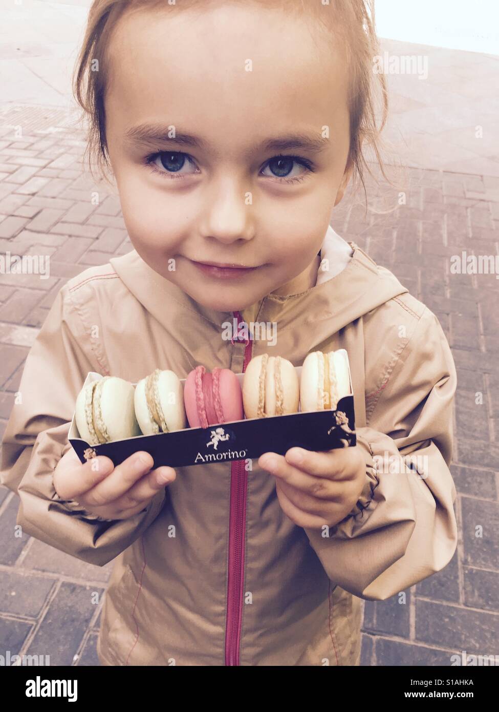 Little girl holding pack with macarons. Various flavors. Stock Photo