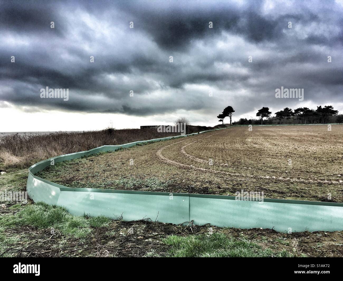Fence around a field to allow counting of wild animals before the land can be used for tunnels for underground electricity cables from an off-shore wind farm, Bawdsey, Suffolk, UK. - Smartphone Captured Stock Image