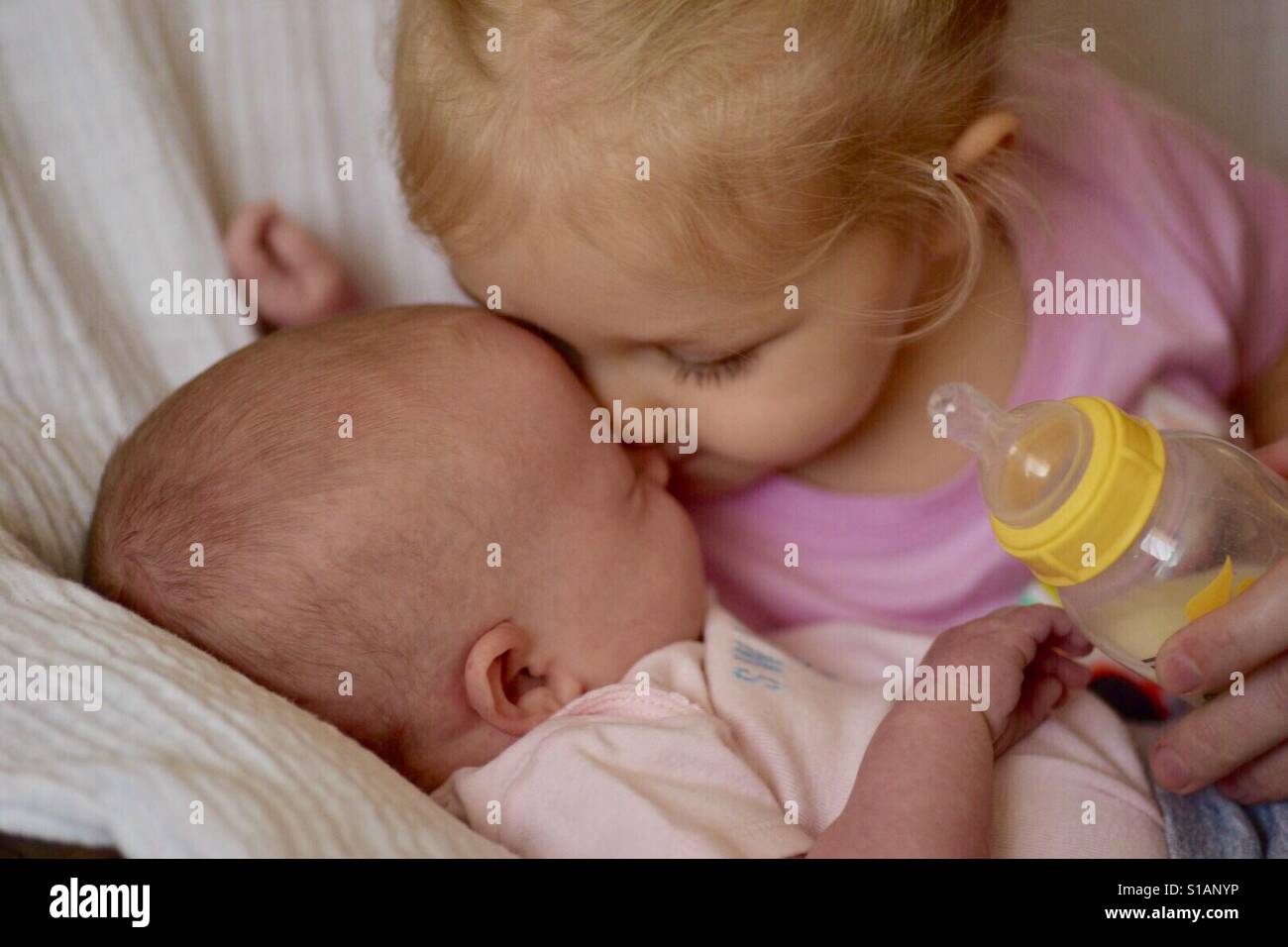 brother feeding little sister with milk or cereal with a bottle Stock Photo
