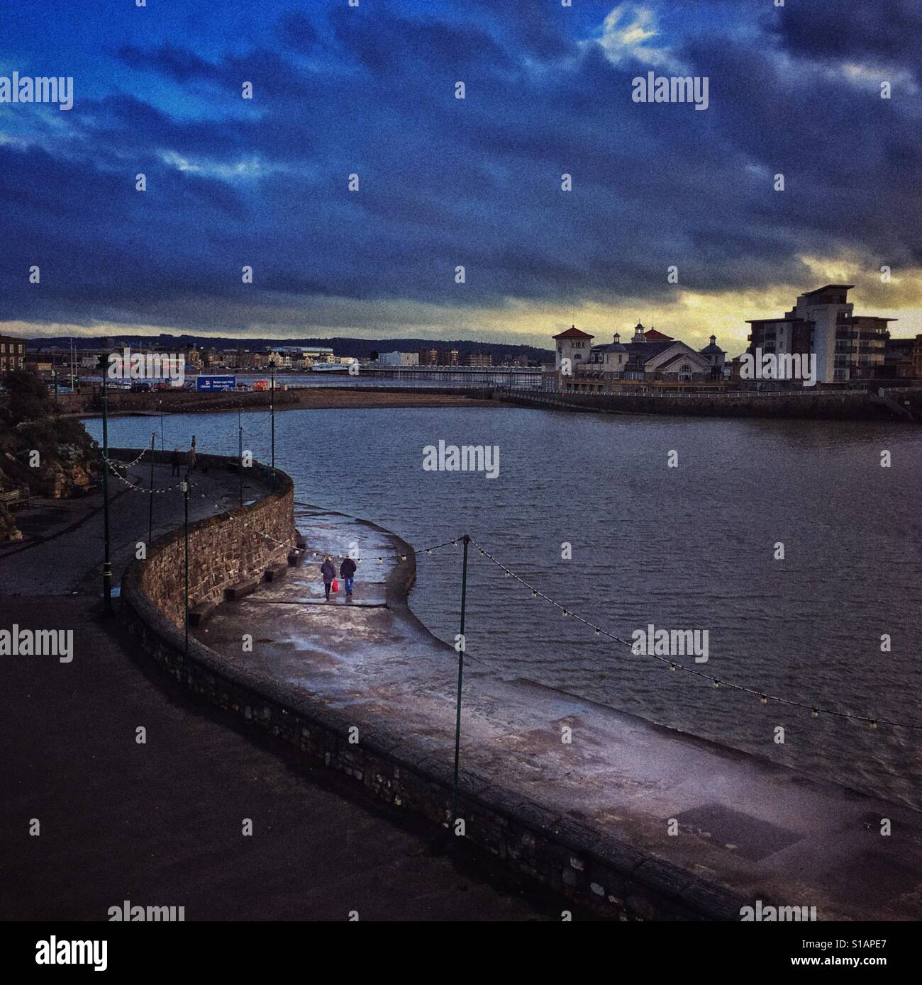 A couple walking on the walkway around the Marine Lake, Weston super Mare, North Somerset, England - Smartphone Captured Stock Image