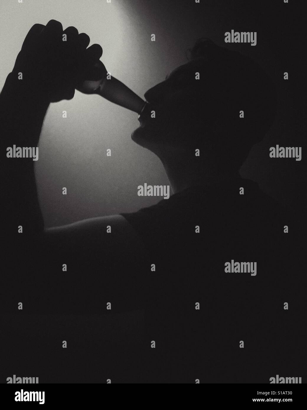 Silhouette of a young man drinking beer from a bottle. In black and white. - Smartphone Captured Stock Image