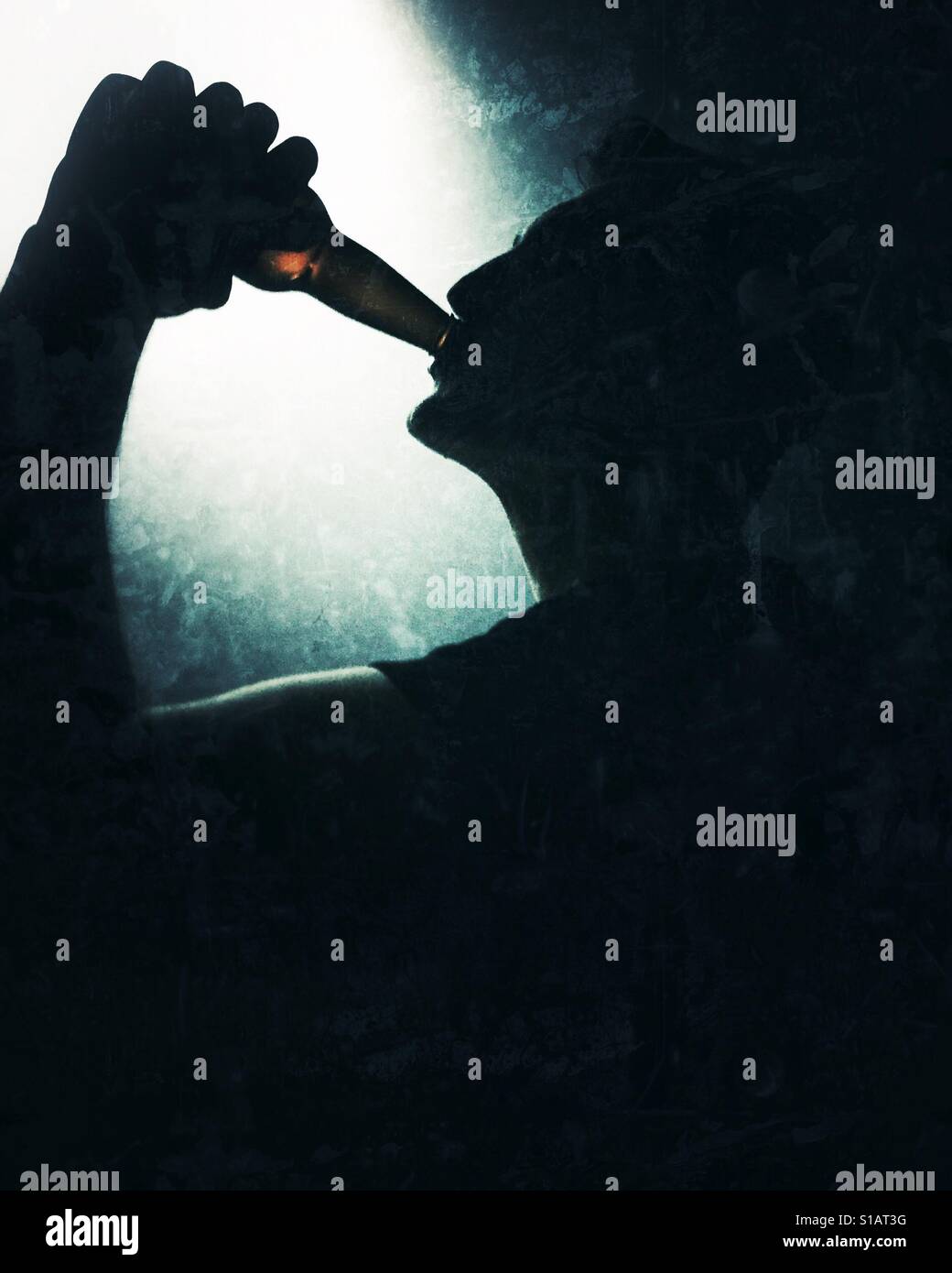 Silhouette of a young man drinking from a glass bottle. - Smartphone Captured Stock Image