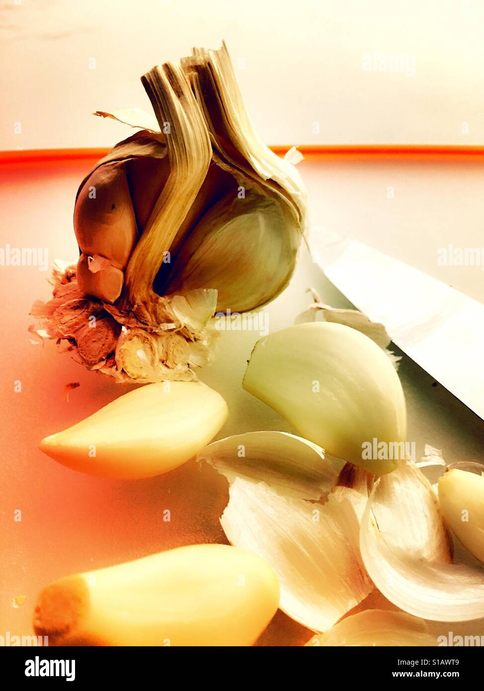 Garlic bulb, cloves on cutting board with knife - Smartphone Captured Stock Image