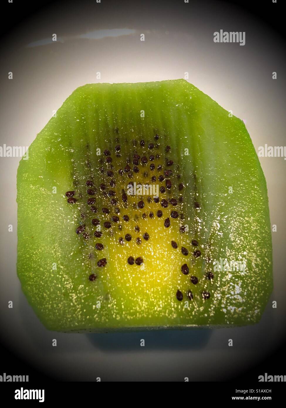 Juicy Kiwi fruit sliced vertically showing small, black seeds - Smartphone Captured Stock Image