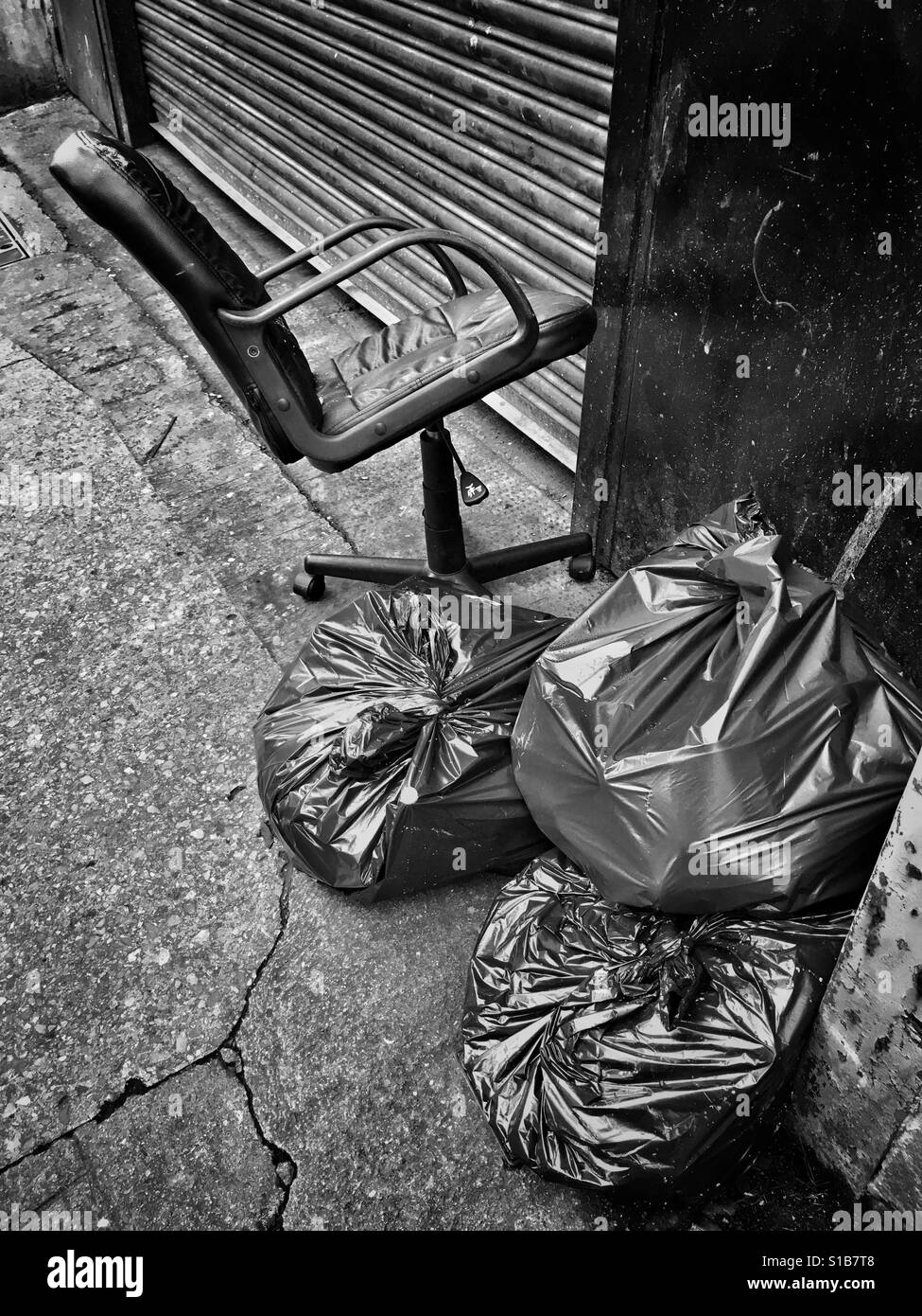 An office chair abandoned next to some rubbish sacks on a street in Bristol, UK - Smartphone Captured Stock Image