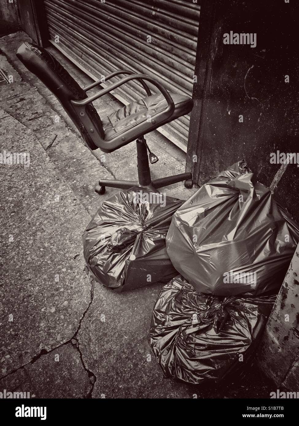 An office chair abandoned next to some rubbish sacks on a street in Bristol, UK - Smartphone Captured Stock Image