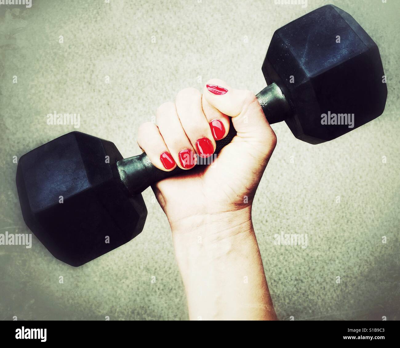 Close up of a manicured woman's hand holding onto an eight pound dumbbell. - Smartphone Captured Stock Image