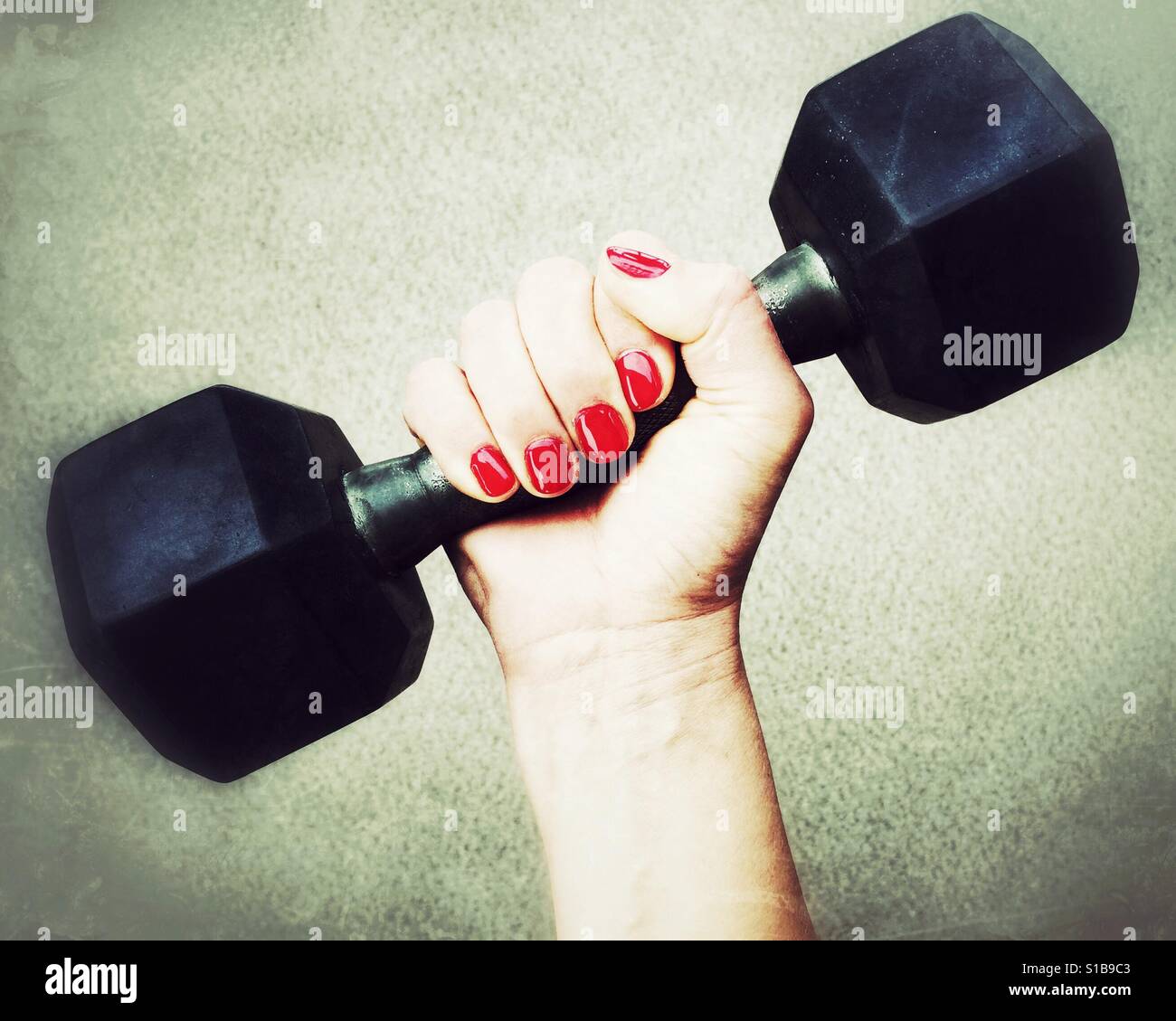 Close up of a manicured woman's hand holding onto an eight pound dumbbell. Stock Photo
