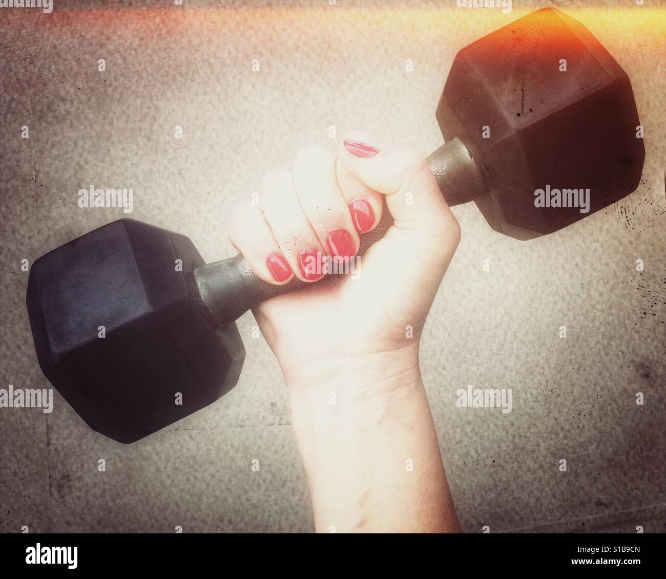 Woman's hand holding onto a dumbbell weight. Light leak. - Smartphone Captured Stock Image